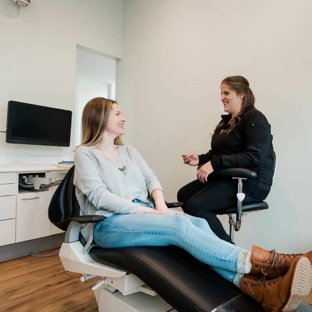 Photo of a Thrive Dental team member talking with a patient sitting in a dental chair