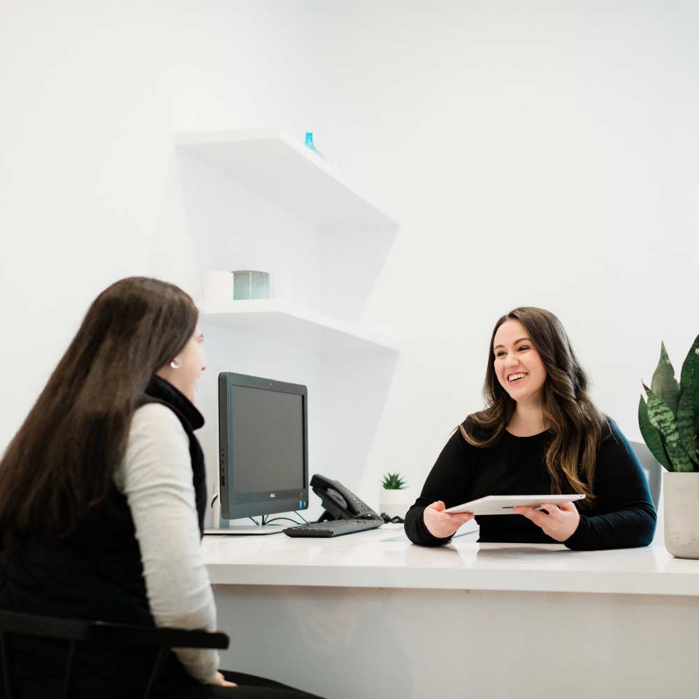 Photo of a Thrive Dental Co. team member sitting behind a desk showing a document to a patient
