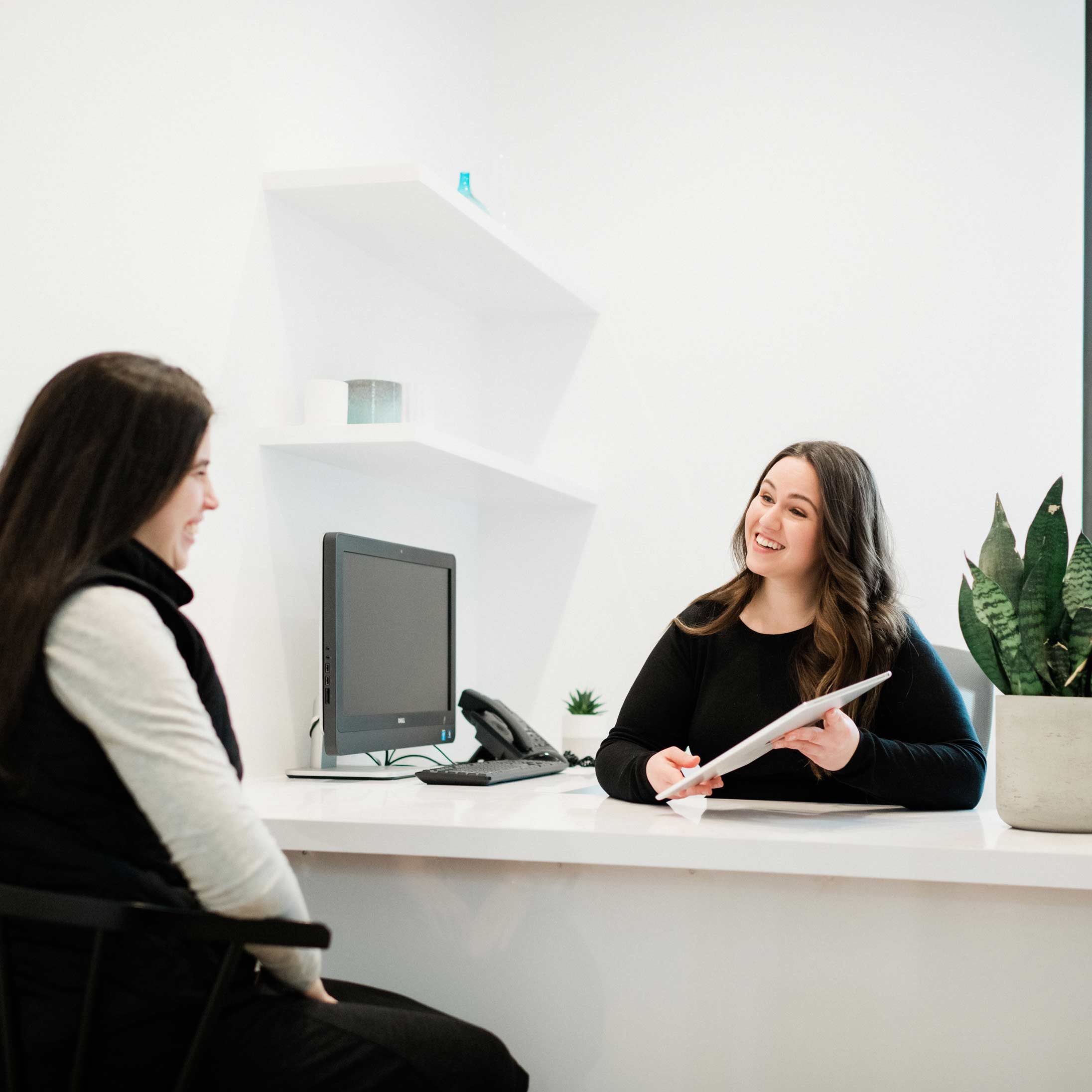 Photo of a team member sitting at a desk showing an iPad to a patient