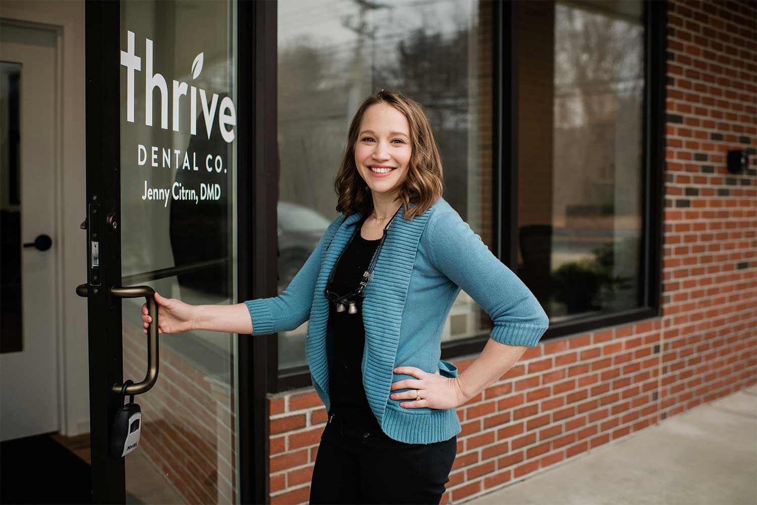 Photo of Acton, MA dentist Jenny Citrin, standing outside the front door of her dental practice