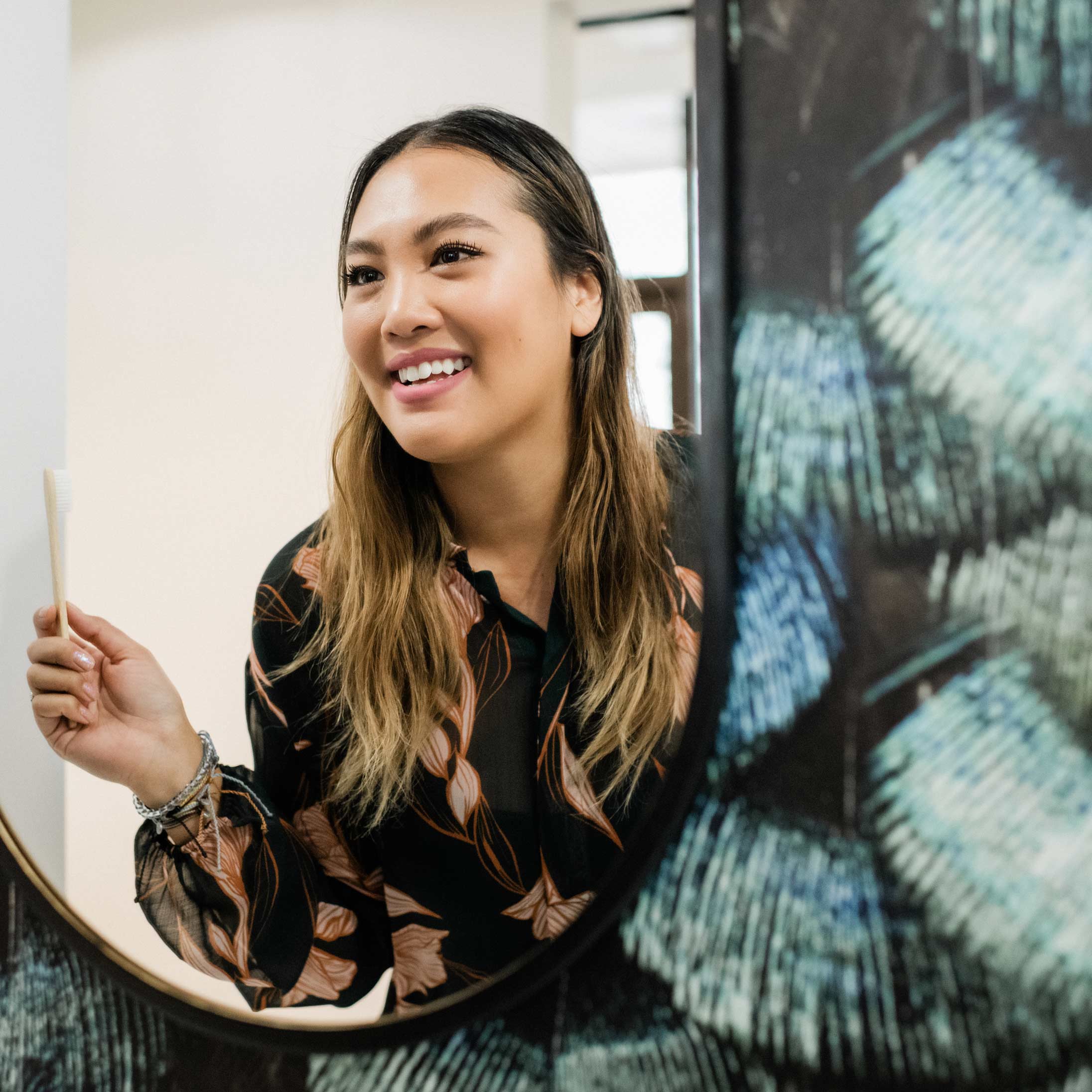 Photo of a smiling patient looking at herself in the mirror